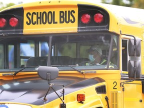 A masked bus driver pulls out of Ecole L'Envolee in Windsor on Sept. 9, 2020. A local school board trustee wants all students, even the youngest, to be required to wear face masks while on school buses.