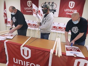 Unifor Local 444 members Ace Tasevski, left, Marty Smith and Damien Dufault prepare strike signs on Tuesday, October 13, 2020, for a possible strike at the FCA Canada Windsor Assembly plant.