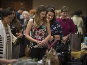 Women look over handbags for auction at last year's 13th annual Do Good Divas signature fundraising event, A Girls Night in Handbag Heaven, at the Caboto Club, Oct. 24, 2019. This year's event goes virtual.