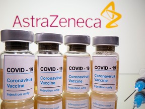 Vials with a sticker reading, "COVID-19 / Coronavirus vaccine / Injection only" and a medical syringe are seen in front of a displayed AstraZeneca logo in this illustration taken October 31, 2020.