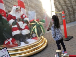 Bella Rivait, age seven, chats with Santa in his snow globe on Maiden Lane in downtown Windsor on Nov. 28, 2020.