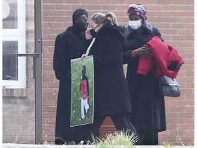 A woman carries a photo into the Windsor Seventh-day Adventist Church on Saturday, Nov. 21, 2020 for the funeral of Kuothhorko (Kuzi) James.