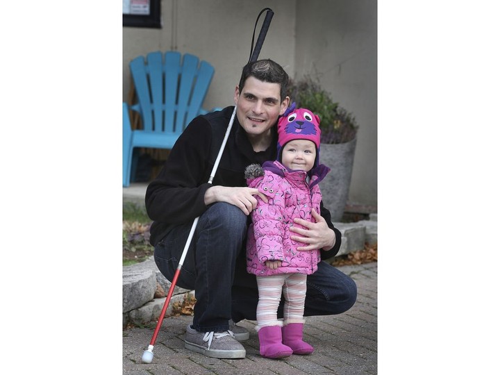  Ryan Hooey is shown on Saturday, November 14, 2020, with his daughter Abigail, 1, near his Tecumseh residence. Hooey lost his sight at 27 due to diabetes and is urging manufacturers to create insulin pumps for those with vision impairment.