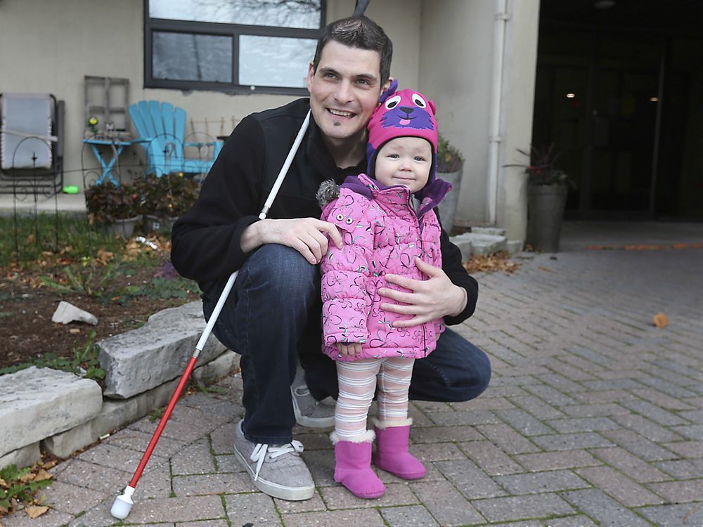 Ryan Hooey is shown on Saturday, November 14, 2020, with his daughter Abigail, 1, near his Tecumseh residence. Hooey lost his sight at 27 due to diabetes and is urging manufacturers to create insulin pumps for those with vision impairment.