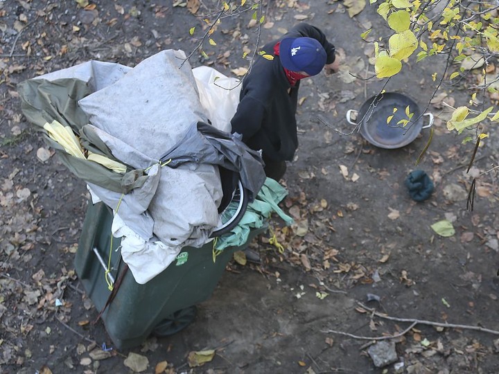  In this file photo from 2020, a homeless man gathers belongings in a garbage container at the “Tent City” created near Caron Avenue and University Avenue West.