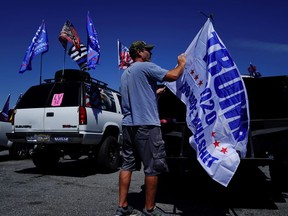 FILE PHOTO: A man attaches a pro-Trump flag to a truck after participating in a caravan convoy in Adairsville, Georgia, U.S. September 5, 2020.