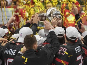 Team Canada players reach for the trophy after defeating Russia 4-3 in the gold medal game earlier this year.