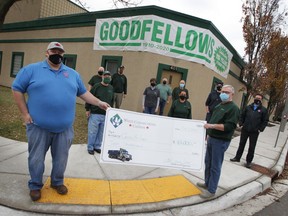 Steve McArthur of Waste Connections of Canada hands a cheque for $10,000 to Art Reid, president of Windsor Goodfellows as other Goodfellows volunteers and representatives from the donating company physically distance behind them on Tuesday, Dec. 8, 2020.
