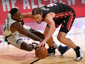 Milwaukee Bucks forward Thanasis Antetokounmpo and Miami Heat forward Kelly Olynyk battle for a loose ball during the first half at American Airlines Arena.
