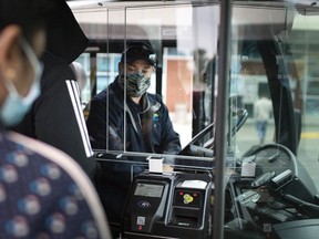 A Transit Windsor bus driver sits behind a protective plastic shield while he waits for passengers to embark outside the Windsor International Transit Terminal on Oct. 26, 2020.