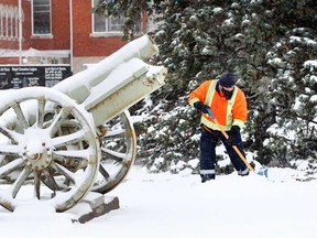 Town of Essex employee Richard Turton shovels snow near the First World War howitzer cannon at Essex Town Hall on Talbot Street South on Dec. 1, 2020.