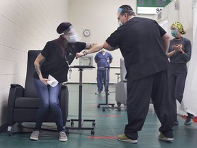 Krystal Meloche, a personal support worker at Seasons Belle River gets an elbow bump from Windsor Regional Hospital CEO David Musyj after she was the first person in Windsor to receive the Covid-19 vaccine at the St. Clair College SportsPlex on Dec. 22, 2020.
