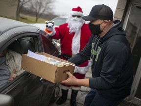 Kevin Beaudoin hands out curbside turkey dinners during the 24th Annual Community Turkey Dinner hosted by the McGregor Squirettes at the McGregor Columbian Club, Sunday, Dec. 20, 2020.