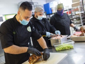 After the community responded to a call for help, Omar Abousaid, left, co-owner of Macro Foods, and Greg Lemay, centre, help prepare Christmas Eve meals for the less fortunate on Wednesday, Dec. 23, 2020. The volunteer effort will see triple the number of households supported this year.