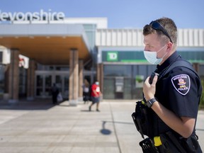 In an Aug. 22 file photo, a Windsor police officer patrols outside an entrance to Devonshire Mall as a small group of people opposed to wearing masks in public show up for a planned shopping trip, while others donned costumes and marched outside.