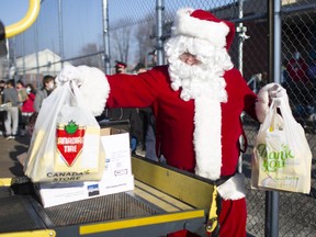 Grade 7 and 8 students from St. Angela Catholic Elementary School get help from Santa as they load donated toys and food items for the Windsor-Essex Children's Aid Society and Advocating Young Minds, Thursday, Dec. 10, 2020.