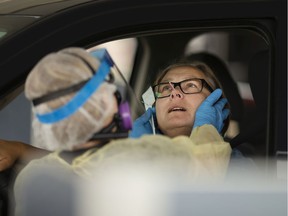 Patricia Zurczak gets tested for COVID-19 by an EMS paramedic at a drive-thru location in the SilverCity Windsor Cinemas parking lot on May 29, 2020.