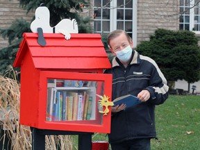 Adrian Lancop at his Snoopy library stand on Linwood Drive in Amherstburg Thursday.  Lancop swaps out the entire book inventory with new books every week and area residents are welcome to take books free of charge.  And, if you happen to be walking your dog, take a dog treat, too.