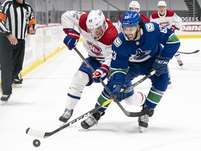 Jalen Chatfield of the Vancouver Canucks battles with Artturi Lehkonen of the Montreal Canadiens for the loose puck during NHL hockey action at Rogers Arena on January 20, 2021 in Vancouver, Canada.