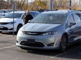 In this Nov. 10, 2020, photo, sales consultant Ryan Eddy walks past a 2017 Chrysler Pacifica Hybrid at Provincial Chrysler.