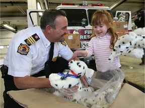 In this Dec. 18, 2007, file photo, then-assistant fire chief John Quennell of the Windsor Fire and Rescue Services gets a hand unloading teddy bears from Madison Coste at the downtown fire station. Madison's mother Jolene Coste was a teacher at Villanova High School where students raised money to buy the stuffed dalmations for donation to other children.