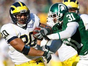 Running back Mike Hart of the Michigan Wolverines protects the football as he tries to break a tackle by cornerback Ashton Henderson of the Michigan State Spartans during the first half at Spartan Stadium November 3, 2007 in East Lansing, Michigan.
