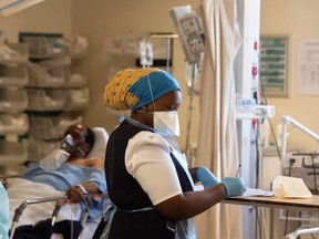 A hospital worker (R) and patient (L) with COVID-19 are seen in in the Resuscitation room of the COVID-19 ward at Khayelitsha Hospital, about 35km from the centre of Cape Town, on December 29, 2020.