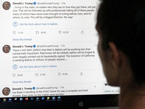 This illustration photo shows an editor in Los Angeles looking at the official Twitter account of US President Donald Trump on May 26, 2020, with two tweets by the president under which Twitter posted a link reading "Get the facts about mail-in ballots".