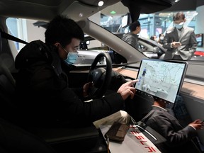 A man checks the dashboard touch screen in a Tesla Model Y car at a Tesla showroom in Beijing on January 5, 2021.