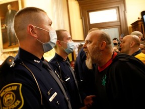 Protestors try to enter the Michigan House of Representative chamber and are being kept out by the Michigan State Police after the American Patriot Rally organized by Michigan United for Liberty protest for the reopening of businesses on the steps of the Michigan State Capitol in Lansing, Michigan on April 30, 2020. - The group is upset with Michigan Gov. Gretchen Whitmer's mandatory closure to curtail Covid-19.