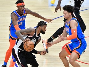 LA Clippers guard Paul George moves the ball past Oklahoma City Thunder forward Isaiah Roby and Oklahoma City Thunder guard Shai Gilgeous-Alexander during the third quarter at Staples Center.