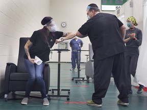 Krystal Meloche, a personal support worker at Seasons Belle River, gets an elbow bump from Windsor Regional Hospital CEO David Musyj on Dec. 22, 2020, after she was the first person in Windsor to receive the COVID-19 vaccine at the St. Clair College SportsPlex.