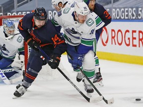 Edmonton Oilers forward Devin Shore and Vancouver Canucks defensemen Nate Schmidt battle for a loose puck during the third period at Rogers Place.