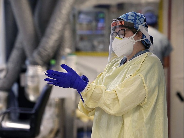  Registered nurse Michelena Sockett dons personal protective equipment during at shift on Jan. 18, 2021, at the Met campus ICU.