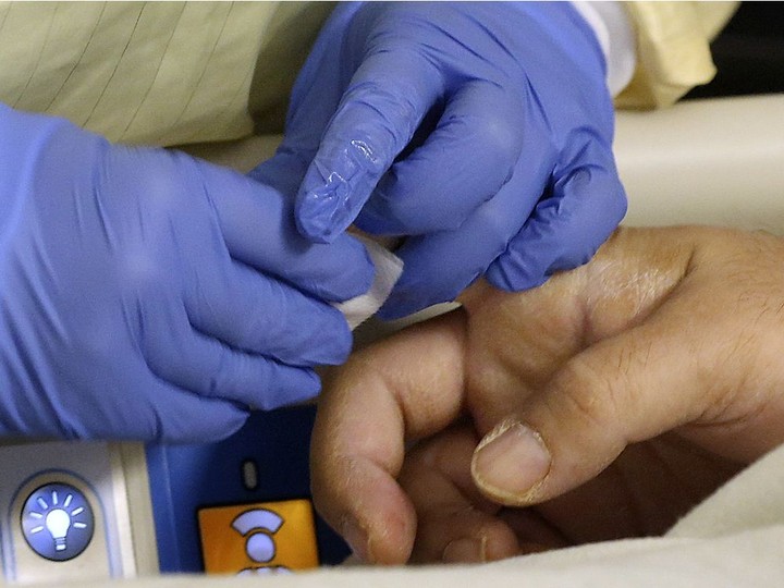  Caring touch. A staff member in the intensive care unit prepares to take a blood sample from a COVID-19 patient on Monday.