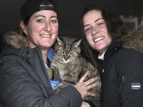 Gina Henderson, left, and her girlfriend Jodie Anderson pose with their cat Hunter on Tuesday, January 26, 2021. Braiden Bendzsak, a 9-year-old boy who lives nearby, found the feline after it was missing for 74 days.