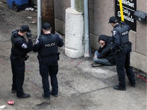 Windsor police officers stand by a man in apparent distress in a downtown alley the morning of March 3, 2020, while waiting for paramedics to arrive. Civilian experts could soon be accompanying local officers responding to mental health calls.