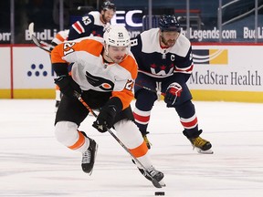 Philadelphia Flyers centre Scott Laughton (21) skates with the puck as Washington Capitals left wing Alex Ovechkin (8) chases at Capital One Arena.