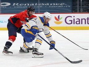 Justin Schultz of the Washington Capitals and Taylor Hall of the Buffalo Sabres go after the puck at Capital One Arena on January 24, 2021 in Washington.