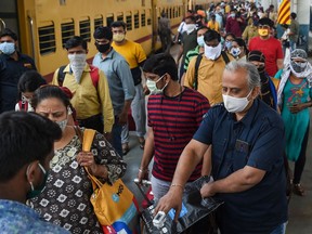 Passengers stand in a queue for a Covid-19 coronavirus medical screening after arriving at a railway platform, in Mumbai on February 17, 2021.