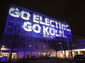 A building of the assembly plant of US car maker Ford is illuminated with the lettering 'Go electric, go Koeln' in Cologne, western Germany, on February 17, 2021. - US auto giant Ford said on February 17, 2021 it was investing one billion dollars in Germany in a bid to make all of its passenger vehicles sold in Europe electric by 2030. The company said in a statement that "by mid-2026, 100 percent of Ford's passenger vehicle range in Europe will be zero-emissions capable, all-electric or plug-in hybrid, and will be completely all-electric by 2030". It said it would upgrade its assembly plant in Cologne, the home of Ford Europe, with a USD 1-billion (830-million-euro) investment to advance the company's "all-electric future".