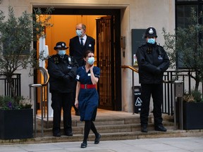 A nurse walks past police officers on duty at the main entrance to King Edward VII hospital in central London on February 19, 2021 where Britain's Prince Philip, Duke of Edinburgh was admitted. - The 99-year-old was taken to the private King Edward VII Hospital on February 16, the palace said, adding that it was a precautionary measure.