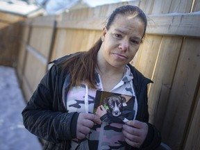 Crystal Lajeunesse holds a photo Thursday of her dog, King, an American bull terrier/lab mix, taken when She's standing in front of a fence she recently had built in her yard, as she attempts to bring home her condemned dog.