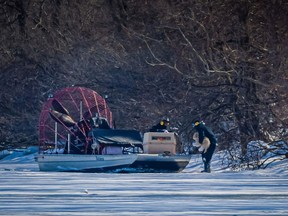 Jude Mead Jr. of J & J Marine Ltd. picks up a dog at Detroit's Mud Island on Feb. 20, 2021. His father, Jude Mead Sr., looks on from an airboat.