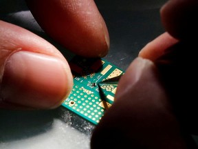 FILE PHOTO: A researcher plants a semiconductor on an interface board during a research work to design and develop a semiconductor product at Tsinghua Unigroup research centre in Beijing, China, February 29, 2016.