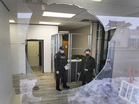 A Windsor police officer speaks with Alexander Reid, executive director of W.E. Trans Support, about a brake rotor that was thrown through a window of the Windsor community organization. Photographed Feb. 22, 2021.