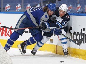 Paul Stastny of the Winnipeg Jets is checked against the boards by Justin Holl of the Toronto Maple Leafs during their game at Scotiabank Arena on March 9, 2021 in Toronto, Ontario, Canada.