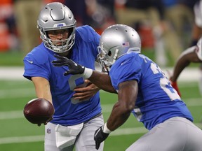 Matthew Stafford of the Detroit Lions hands the ball off to Adrian Peterson during the first half at Ford Field on November 26, 2020 in Detroit, Michigan.