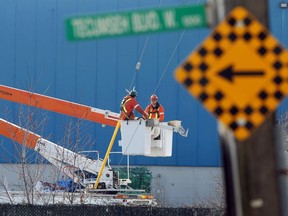 Utility workers use an aerial lift truck to check out power lines on Tecumseh Road West near Wellington Avenue on March 17, 2021.