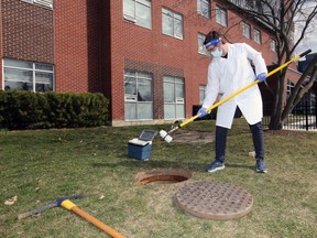 University of Windsor research associate Ryland Corchis-Scott demonstrates how he uses a pole to conduct a "grab sample" of sewer discharge from Alumni Hall Tuesday, March 23, 2021. Corchis-Scott collects about 500 ml per sample which is tested for levels of COVID-19.